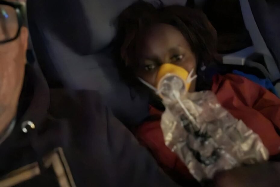 : Linda Chebet Gomez flight medical emergency showing her wearing an oxygen mask on an airplane seat next to her husband.