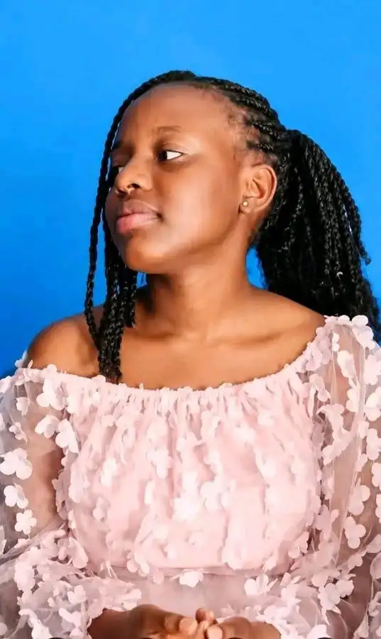 Photo of Laura, a Form Three student at Vokoli Girls High School, wearing a light pink floral off-the-shoulder dress against a blue background.