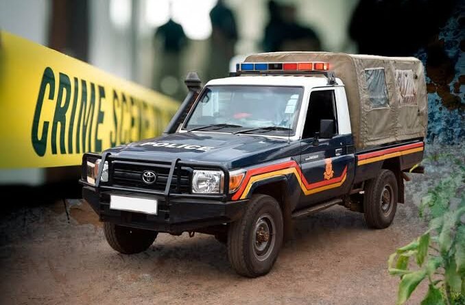 A dark-colored police pickup truck with a snorkel and covered cargo bed is parked on dirt ground next to a large yellow "CRIME SCENE" banner.