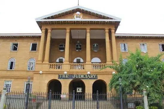 Exterior view of the Law Courts building in Nairobi, Kenya, displaying "THE JUDICIARY" in bold lettering above its arched central entrance.