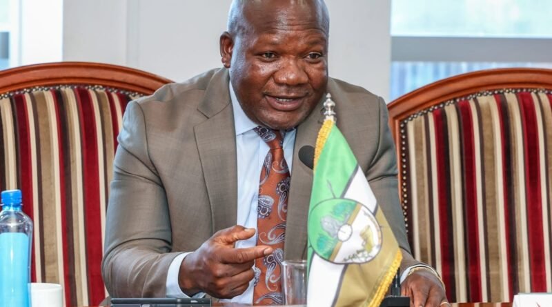 Governor of Kakamega County, H.E. FCPA Fernandes Barasa, speaking during an official meeting seated behind a desk with a county flag and nameplate.