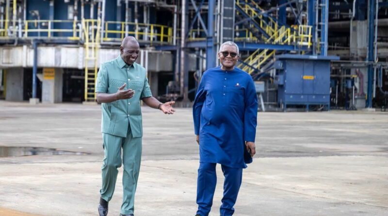 President William Ruto and Aliko Dangote walking and smiling together outdoors at an industrial refinery facility.