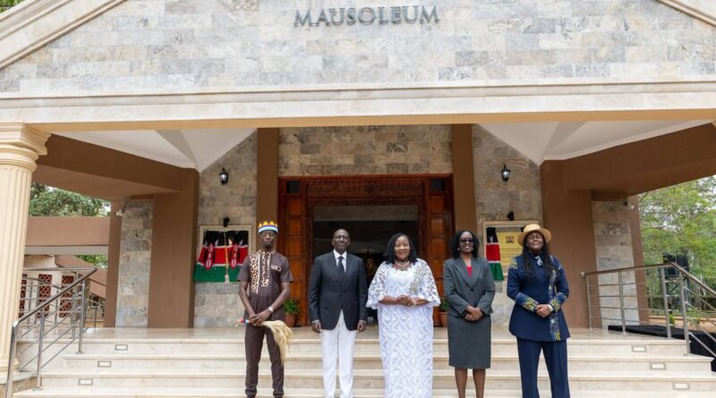 Five people standing outside the Raila Amolo Odinga Mausoleum building in Bondo